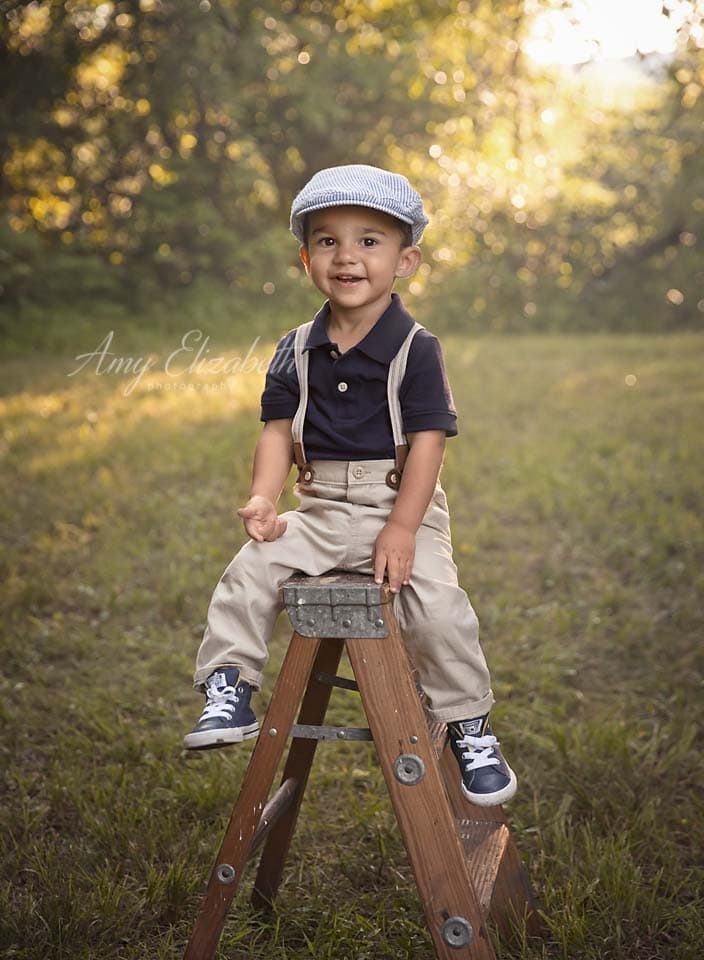 toddler boy in hat on ladder st louis family photographer