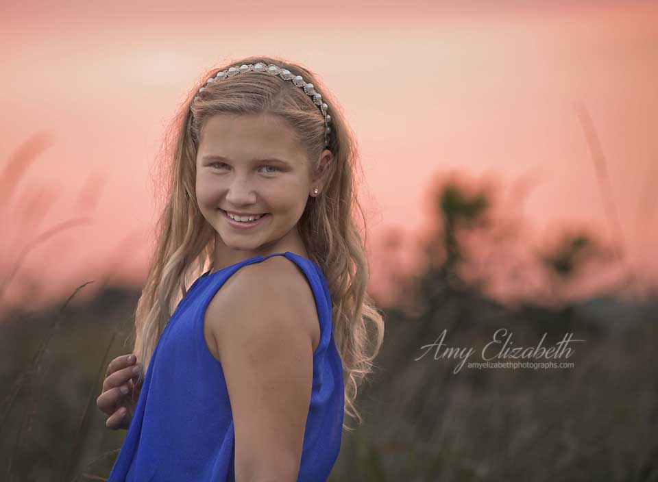 preteen girl in blue dress and pink sky