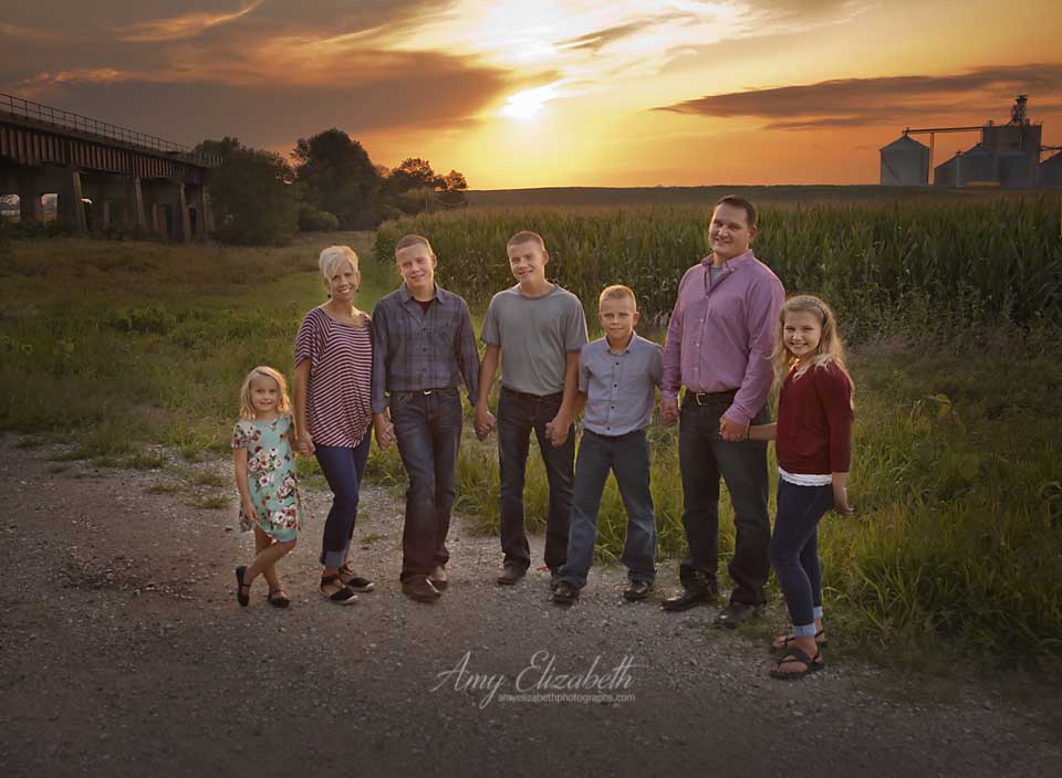 family by cornfield at sunset in manning iowa