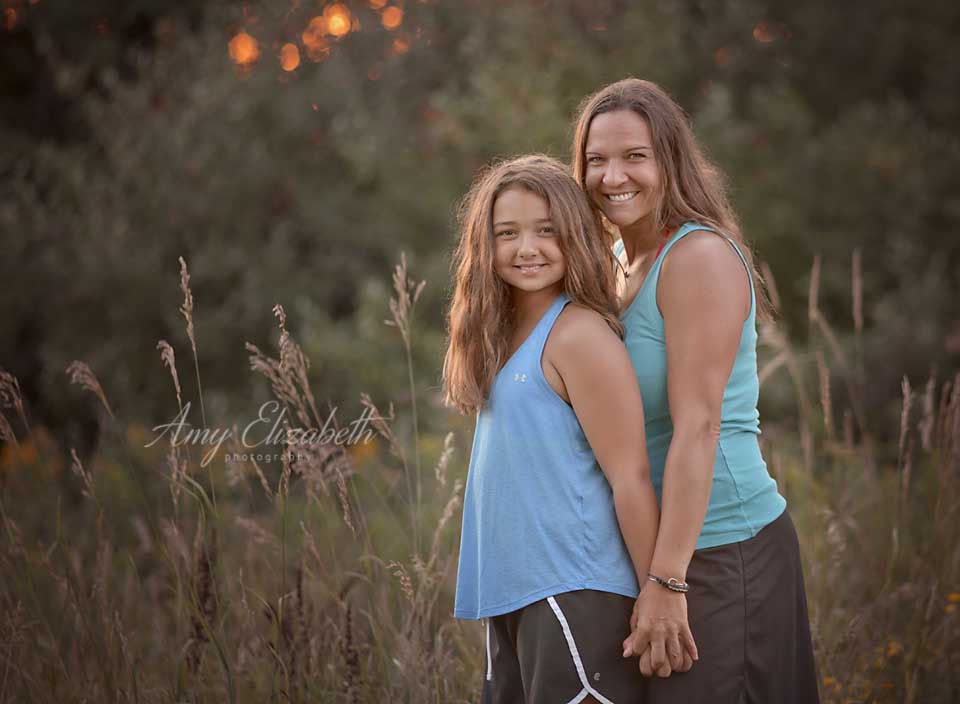 mom and daughter standing by tall grass