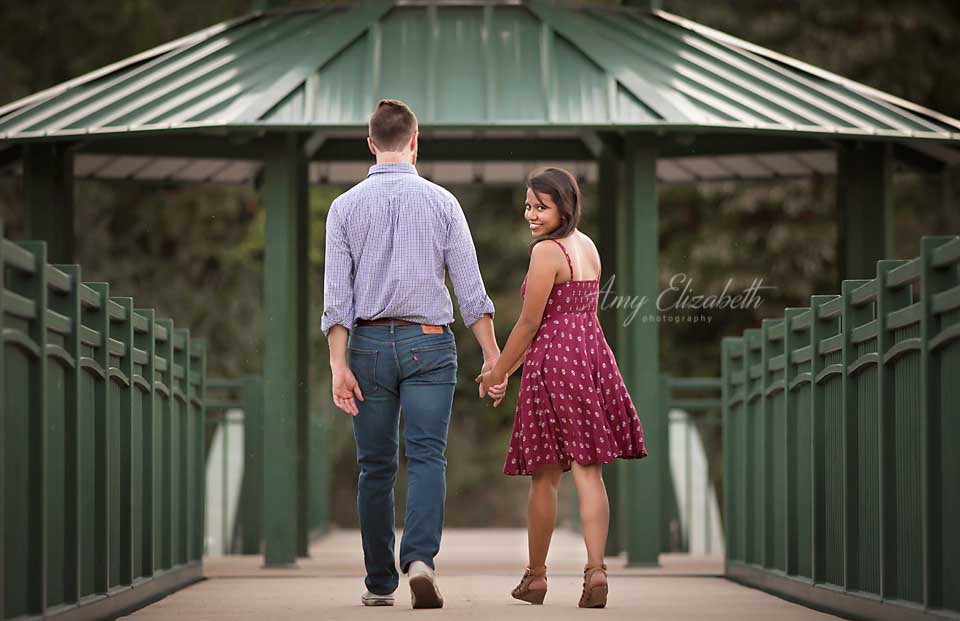 engaged couple walking away on bridge