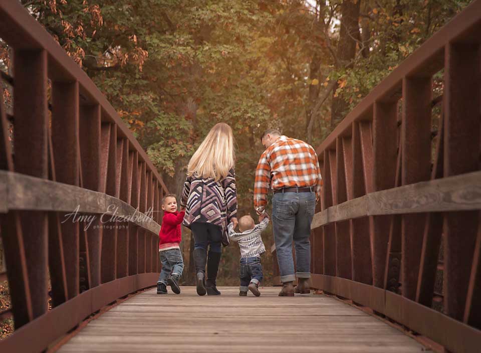 family of four walking away on bridge
