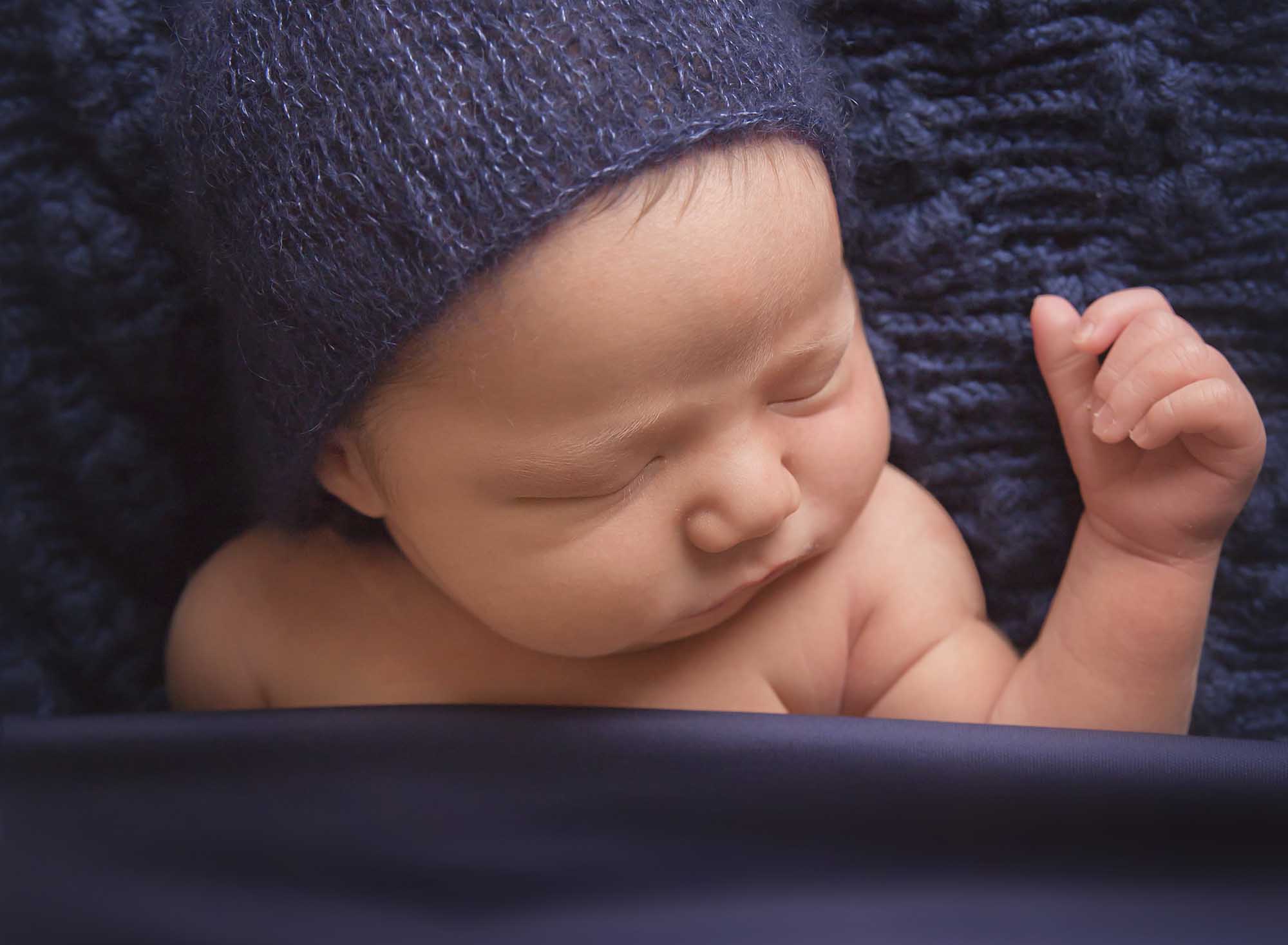 newborn boy tucked in navy blue