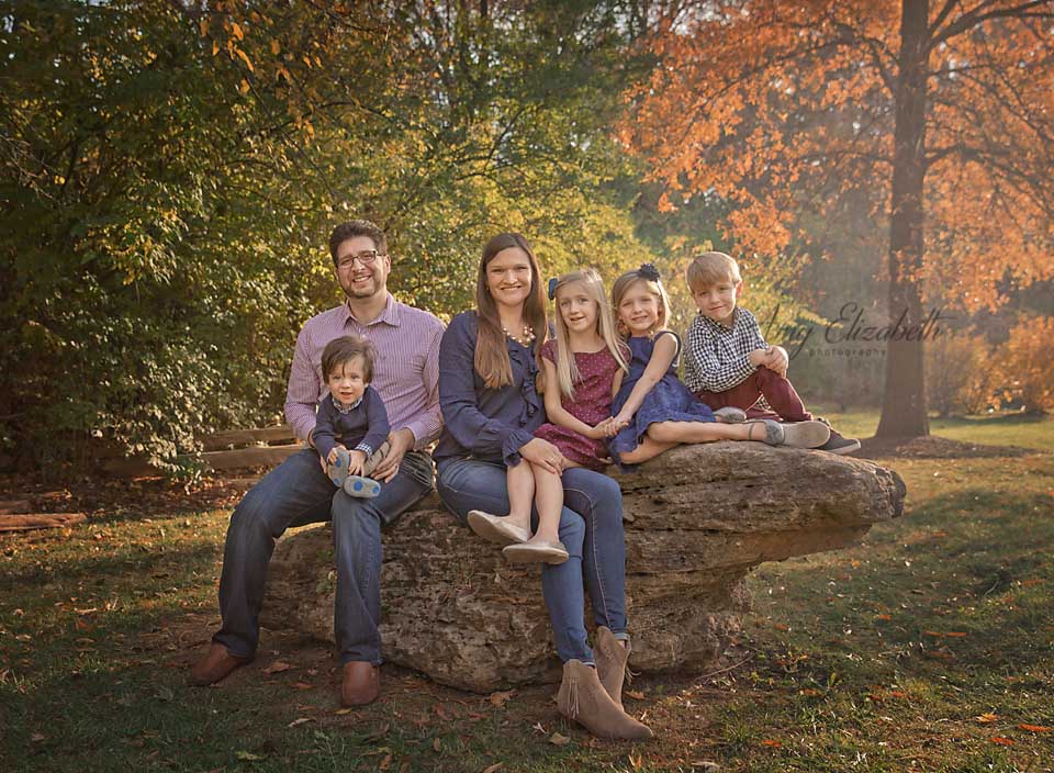 family of six sitting on large rock st. louis photographer