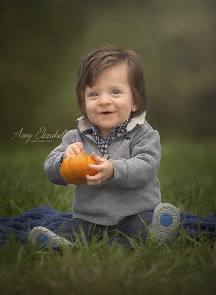baby boy holding pumpkin during sitter photo session